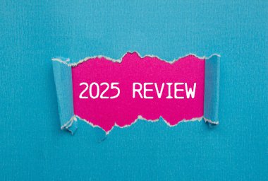 Yırtık mavi kağıda pembe arka plan ile yazılmış 2025 gözden geçirme mesajı. Kavramsal 2025 değerlendirme sembolü. Boşluğu kopyala.