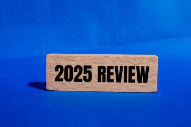 2025 gözden geçirme mesajı ahşap blokta mavi arka planda yazılmış. Kavramsal 2025 değerlendirme sembolü. Boşluğu kopyala.