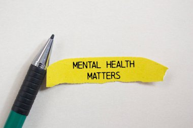 Mental health matters message written on ripped torn yellow paper piece and a pen with white background. Conceptual mental health matters symbol. Copy space. clipart