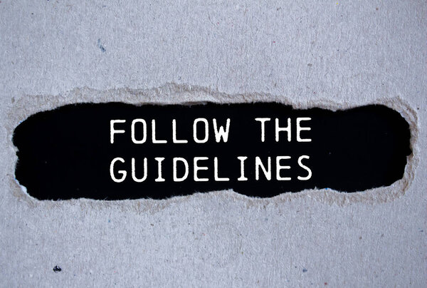 Follow the guidelines message written on ripped torn gray paper with black background. Conceptual follow the guidelines symbol. Copy space.
