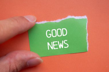 Turuncu arkaplanlı yeşil yırtık kağıda iyi haber mesajı yazılmış. Kavramsal iyi haber sembolü. Boşluğu kopyala.