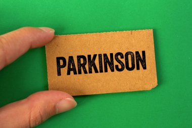 Yeşil arka planda karton kağıda Parkinson mesajı yazılmış. Kavramsal Parkinson sembolü. Boşluğu kopyala.