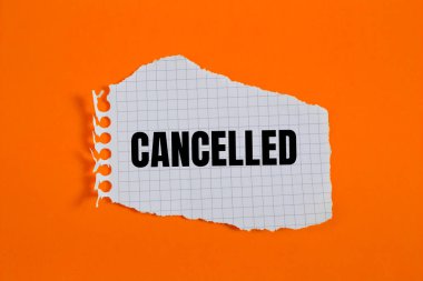 Turuncu arkaplanlı yırtık kareli kağıt parçasına yazılmış ileti iptal edildi. Kavramsal iptal sembolü. Boşluğu kopyala.