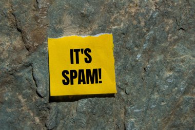 Yırtık sarı kağıt parçasına, taştan arkaplan ile yazılmış spam mesajı. Spam sembolü kavramsal. Boşluğu kopyala.