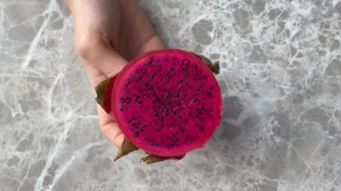 Dilimlenmiş ejderha meyvesi manzaralı kadın eli.