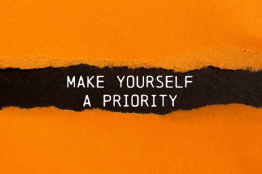 Siyah arkaplanlı yırtık turuncu kağıda yazılmış öncelikli bir mesaj yap. Kavramsal olarak kendini öncelikli bir sembol yap. Boşluğu kopyala.