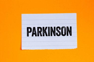 Parkinson mesajı turuncu arka plandaki yırtık beyaz kağıt parçasına yazılmış. Kavramsal Parkinson sembolü. Boşluğu kopyala.