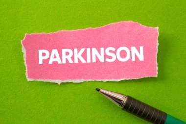Parkinson mesajı yeşil arka plandaki yırtık pembe kağıt parçasına yazılmış. Kavramsal Parkinson sembolü. Boşluğu kopyala.