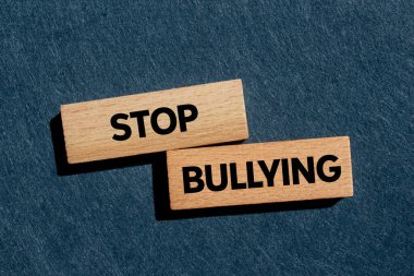 Gri arka planda tahta bloklara yazılmış mesajlara zorbalık etmeyi bırak. Kavramsal zorbalık sembolünü durdur. Boşluğu kopyala.