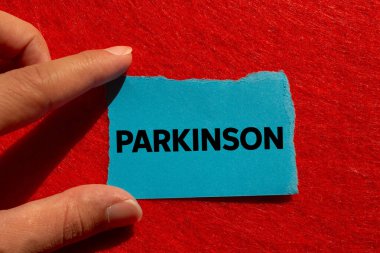 Parkinson mesajı kırmızı arka planda yırtık mavi kağıda yazılmış. Kavramsal Parkinson sembolü. Boşluğu kopyala.