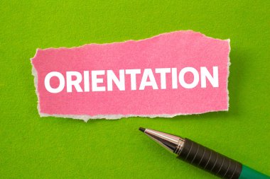 Yeşil arka planda yırtık pembe kağıt parçasına oryantasyon mesajı yazılmış. Kavramsal yönelim sembolü. Boşluğu kopyala.