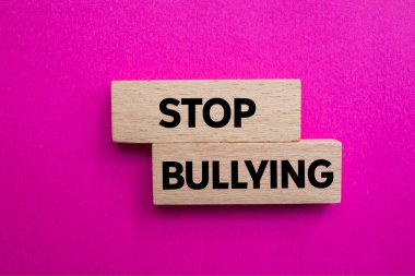 Ahşap bloklara pembe arka planda yazılmış mesajlara zorbalık etmeyi bırak. Kavramsal zorbalık sembolünü durdur. Boşluğu kopyala.