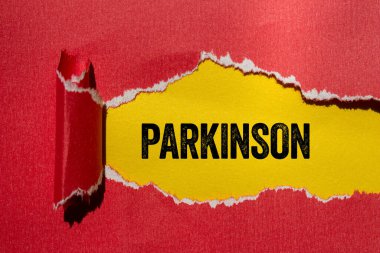 Sarı arka planda yırtık kırmızı kağıda Parkinson mesajı yazılmış. Kavramsal Parkinson sembolü. Boşluğu kopyala.