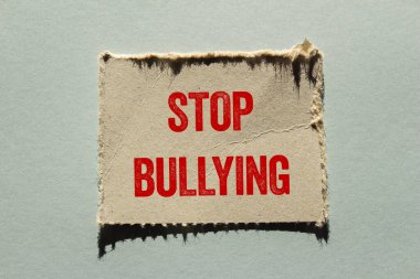 Gri arkaplandaki yırtık kağıt parçasına yazılan mesajlara zorbalık etmeyi bırak. Kavramsal zorbalık sembolünü durdur. Boşluğu kopyala.