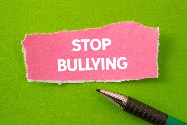 Yeşil arka plandaki yırtık pembe kağıt parçasına yazılan mesajlara zorbalık etmeyi bırak. Kavramsal zorbalık sembolünü durdur. Boşluğu kopyala.