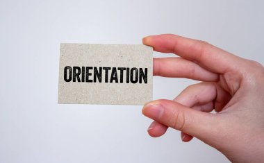 Elindeki bir karta oryantasyon mesajı yazılmış. Kavramsal yönelim sembolü. Boşluğu kopyala.