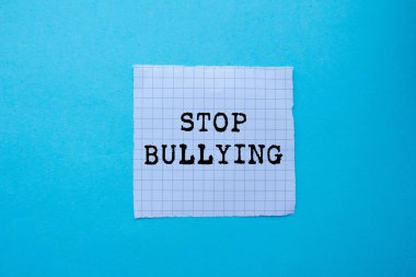 Mavi arka planda yırtık beyaz kağıda yazılan mesajlara zorbalık etmeyi bırak. Kavramsal zorbalık sembolünü durdur. Boşluğu kopyala.