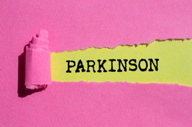 Sarı arka planda yırtık pembe kağıda Parkinson mesajı yazılmış. Kavramsal Parkinson sembolü. Boşluğu kopyala.
