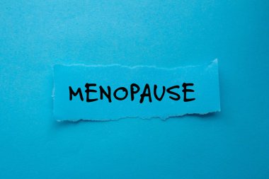 Menopoz mesajı mavi arka plandaki yırtık kağıt parçasına yazılmış. Kavramsal menopoz sembolü. Boşluğu kopyala.