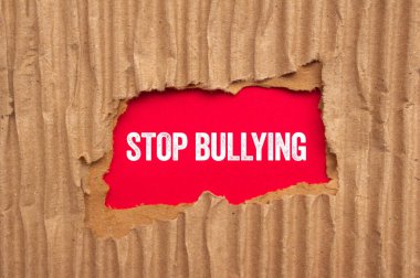 Kırmızı arka planda yırtık karton kağıda yazılmış mesajlara zorbalık etmeyi bırak. Kavramsal zorbalık sembolünü durdur. Boşluğu kopyala.