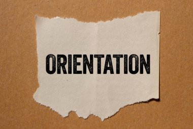 Kahverengi arka planda yırtık kağıt parçasına oryantasyon mesajı yazılmış. Kavramsal yönelim sembolü. Boşluğu kopyala.