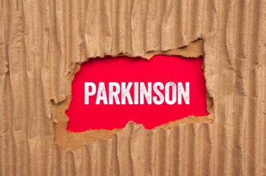 Kırmızı arka planda yırtık karton kağıda Parkinson mesajı yazılmış. Kavramsal Parkinson sembolü. Boşluğu kopyala.
