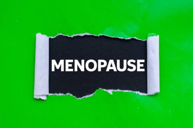 Siyah arka planda yırtık yeşil kağıda yazılmış menopoz mesajı. Kavramsal menopoz sembolü. Boşluğu kopyala.
