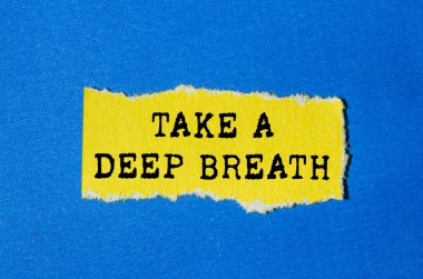 Mavi arka planda yırtık sarı kağıda yazılmış derin bir nefes mesajı alın. Kavramsal bir nefes alma sembolü. Boşluğu kopyala.