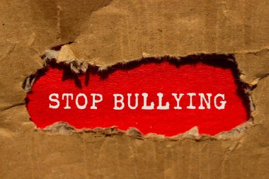 Kırmızı arka planda yırtık karton kağıda yazılmış mesajlara zorbalık etmeyi bırak. Kavramsal zorbalık sembolünü durdur. Boşluğu kopyala.