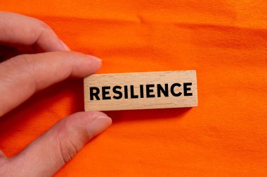 Dayanıklılık mesajı turuncu arka plandaki tahta bloğa yazılmış. Kavramsal esneklik sembolü. Boşluğu kopyala.