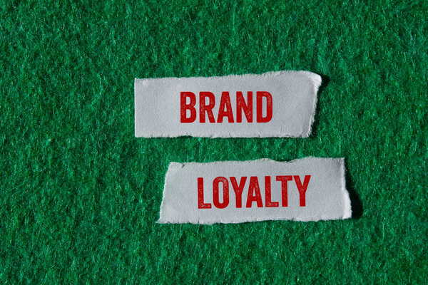 Сообщение о лояльности бренда, написанное на разорванных кусочках бумаги на зеленом фоне. Символ лояльности бренда. Копирование пространства.