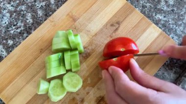 Domates ve salatalığı dilimleyen bir el Mutfakta bir kesim tahtasının üzerinde