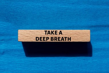 Mavi arka plandaki tahta bloğa yazılmış derin bir nefes mesajı alın. Kavramsal bir nefes alma sembolü. Boşluğu kopyala.