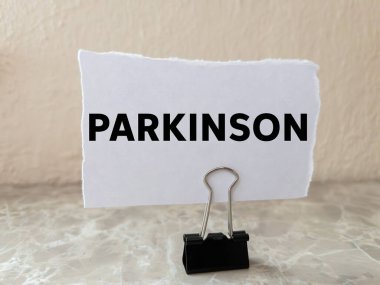 Parkinson mesajı arka plandaki yırtık beyaz kağıt parçasına yazılmış. Kavramsal Parkinson sembolü. Boşluğu kopyala.