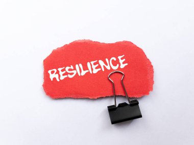 Beyaz zemin üzerindeki yırtık kırmızı kağıt parçasına yazılan dayanıklılık mesajı. Kavramsal esneklik sembolü. Boşluğu kopyala.