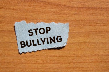 Ahşap arka planda yırtık gri kağıt parçasına yazılan mesajlara zorbalık etmeyi bırak. Kavramsal zorbalık sembolünü durdur. Boşluğu kopyala.