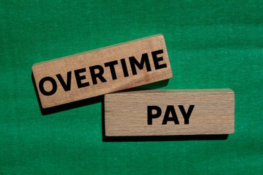 Fazla mesai ödemesi mesajı yeşil arka plandaki tahta bloklara yazılmış. Kavramsal fazla mesai ödeme sembolü. Boşluğu kopyala.