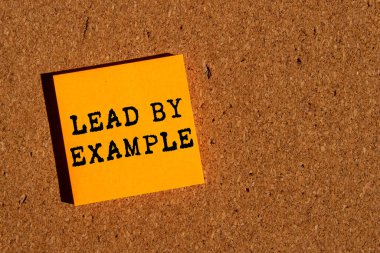 Kahverengi arka planda turuncu kağıda yazılmış örnek bir mesajla. Örnek sembolle kavramsal liderlik. Boşluğu kopyala.