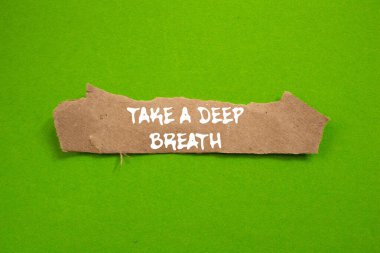 Yeşil arka planda yırtık kahverengi kağıt parçasına yazılmış derin bir nefes mesajı alın. Kavramsal bir nefes alma sembolü. Boşluğu kopyala.