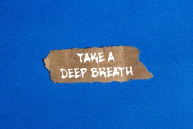 Mavi arka planda yırtık kahverengi kağıt parçasına yazılmış derin bir nefes mesajı alın. Kavramsal bir nefes alma sembolü. Boşluğu kopyala.