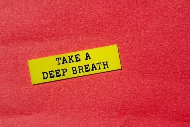 Kırmızı arka planda sarı kağıt üzerine yazılmış derin bir nefes mesajı alın. Kavramsal bir nefes alma sembolü. Boşluğu kopyala.