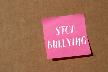 Kahverengi arka planda pembe kağıda yazılmış mesajlara zorbalık etmeyi bırak. Kavramsal zorbalık sembolünü durdur. Boşluğu kopyala.