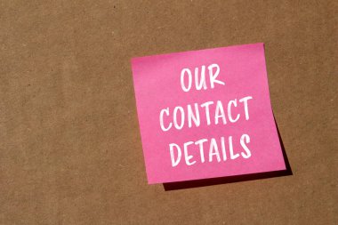 Temas bilgilerimiz kahverengi arka planda pembe kağıda yazılmış. İletişim detaylarının sembolü kavramsal. Boşluğu kopyala.