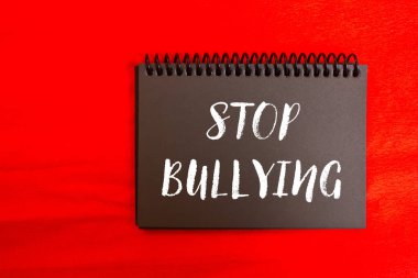 Kırmızı arkaplanda siyah defter sayfasında yazılı olan mesajlara zorbalık etmeyi bırak. Kavramsal zorbalık sembolünü durdur. Boşluğu kopyala.