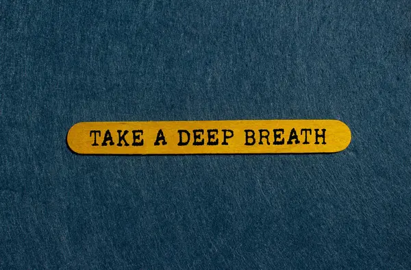 Gri arka planda sarı tahta çubuğa yazılmış derin bir nefes mesajı alın. Kavramsal bir nefes alma sembolü. Boşluğu kopyala.