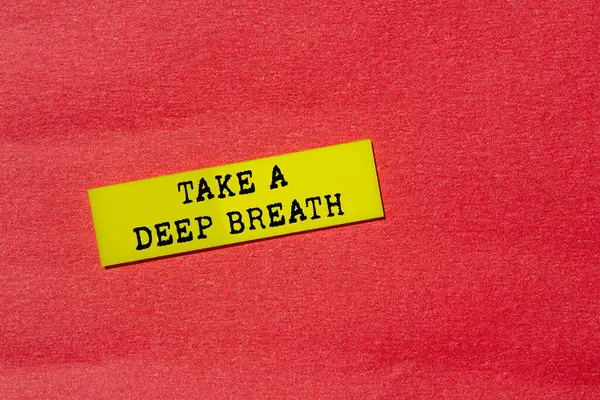 Kırmızı arka planda sarı kağıt üzerine yazılmış derin bir nefes mesajı alın. Kavramsal bir nefes alma sembolü. Boşluğu kopyala.