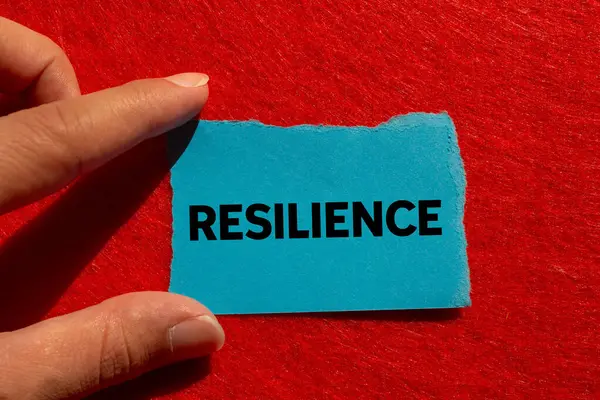 Kırmızı arkaplanda yırtık mavi kağıda yazılmış dayanıklılık mesajı. Kavramsal esneklik sembolü. Boşluğu kopyala.
