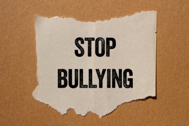 Kahverengi arka planda yırtık kağıt parçasına yazılan mesajlara zorbalık etmeyi bırak. Kavramsal zorbalık sembolünü durdur. Boşluğu kopyala.