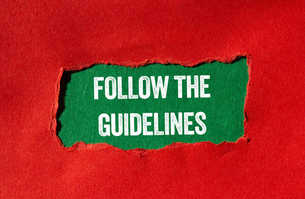 Follow the guidelines message written on ripped torn red paper on green background. Conceptual follow the guidelines symbol. Copy space.