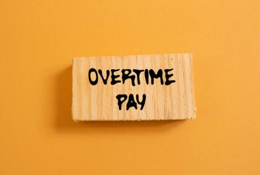 Turuncu arka planda tahta parçasına fazla mesai ödemesi mesajı yazılmış. Kavramsal fazla mesai ödeme sembolü. Boşluğu kopyala.